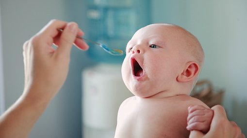 Imagem da mão da mãe oferecendo papinha ao bebê